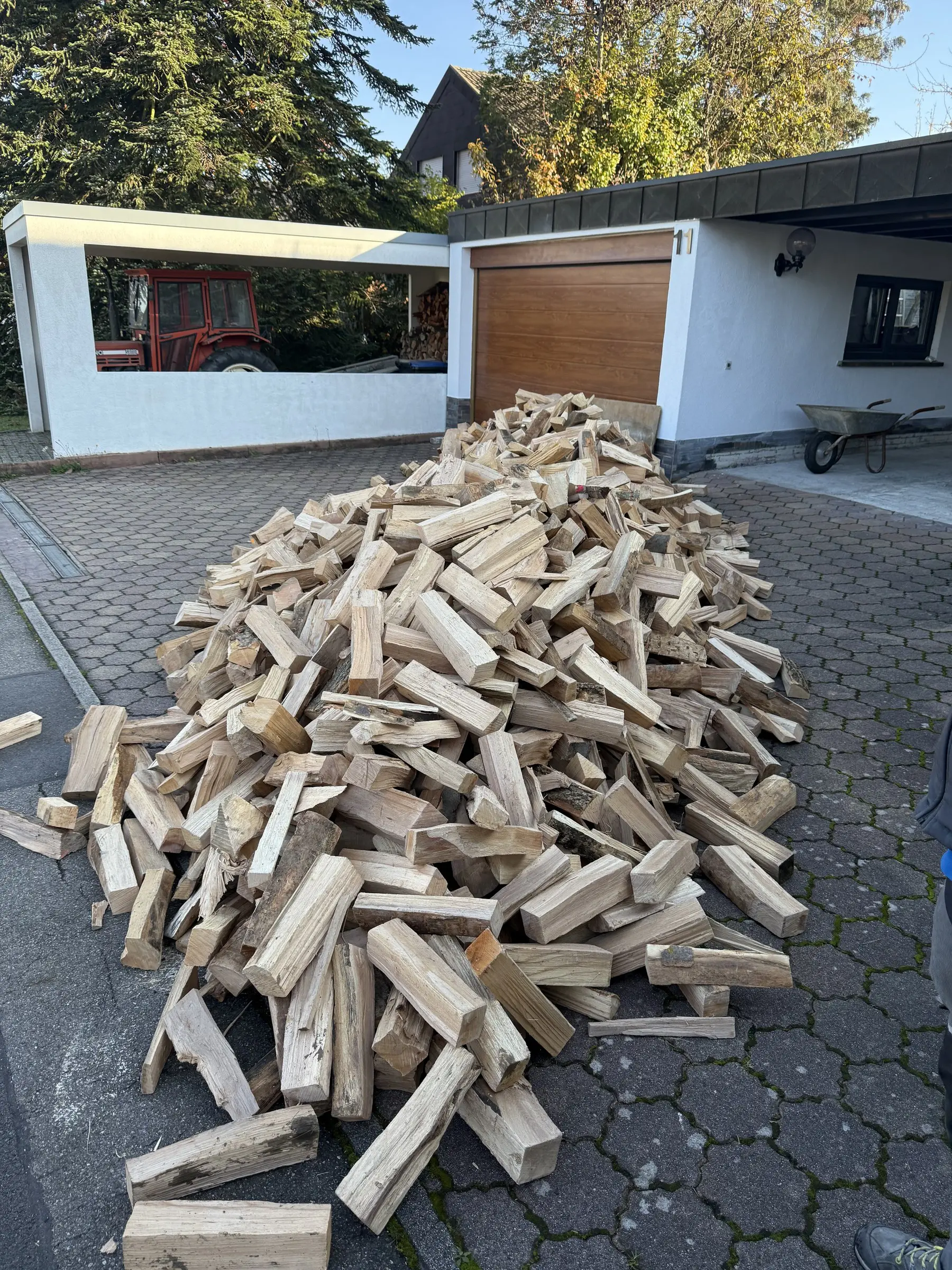 Frisch geliefertes Buchenholz in einer Einfahrt vor der Garage